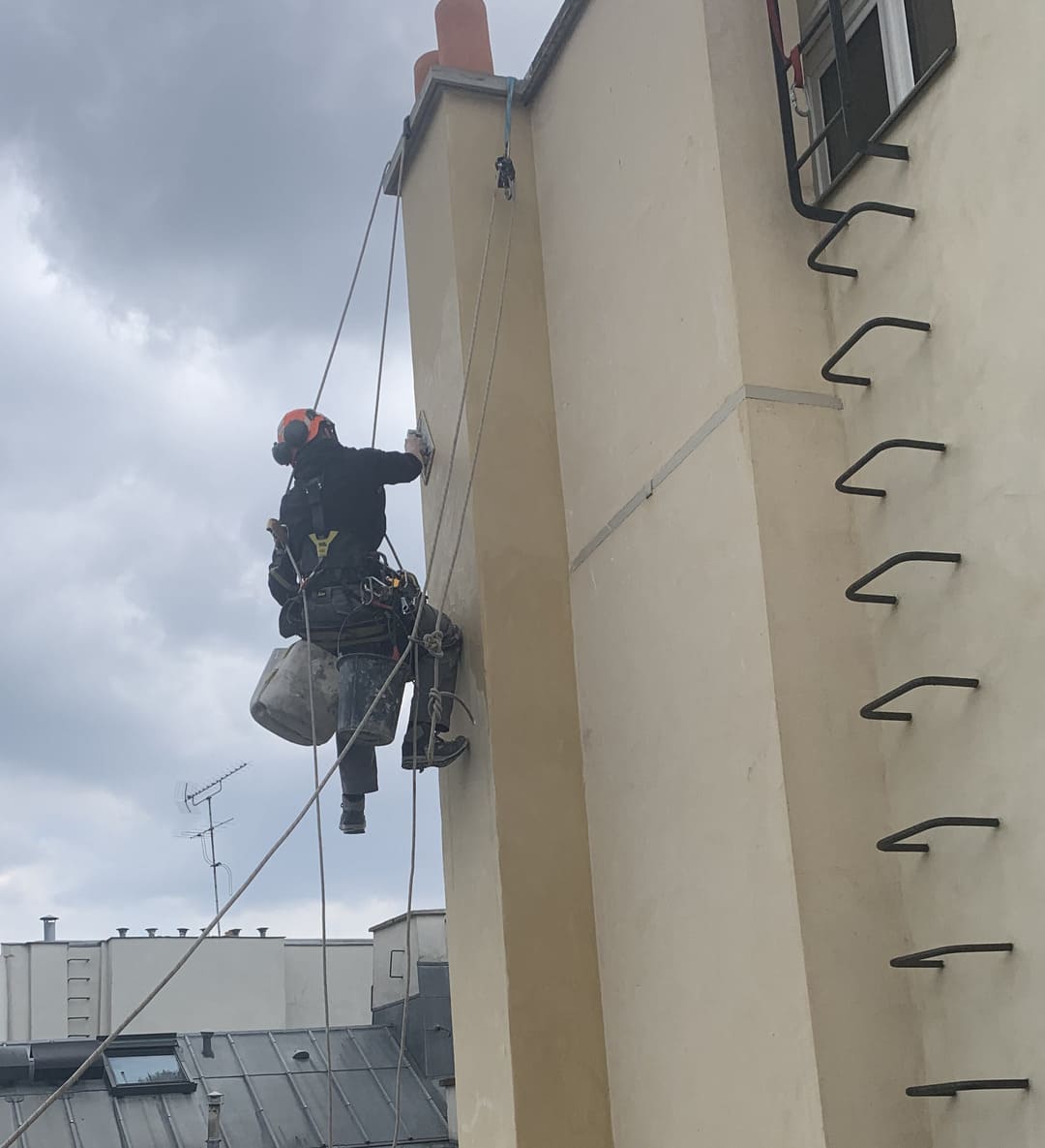 Travaux de maçonnerie en hauteur par cordistes certifiés à Paris Cordiste professionnel effectuant un travail de maçonnerie en hauteur sur une façade d’immeuble à Paris, sécurisé par cordes et harnais.